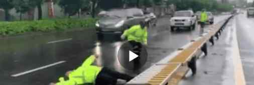 台风天执勤交警扶护栏被压倒  看着都心疼