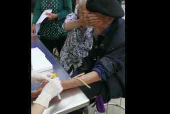 98岁爷爷抽血100岁奶奶帮捂眼睛 究竟是怎么回事?